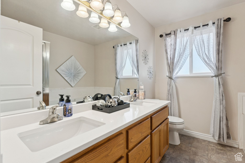 Full bath with double vanity, toilet, and baseboards