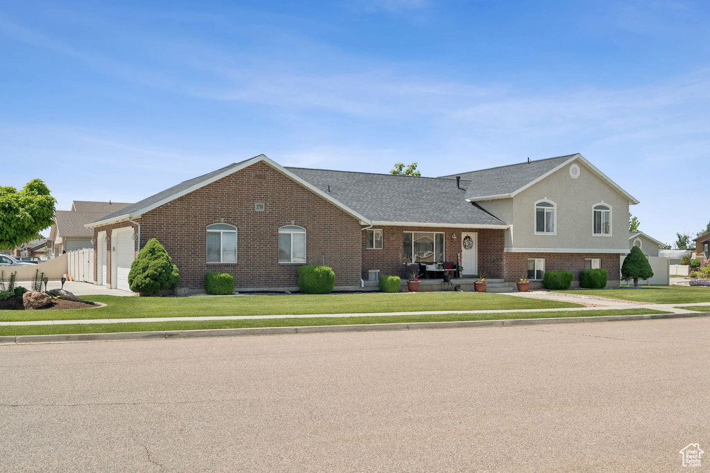 View of front facade with brick siding, a garage, and a shingled roof