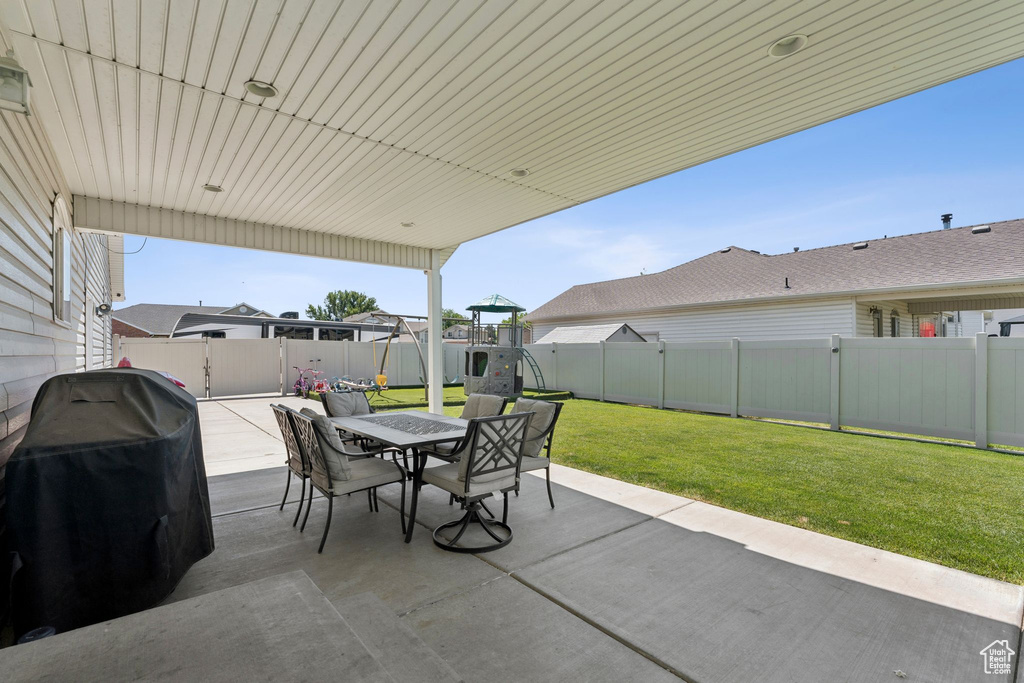 View of patio with outdoor dining space, a playground, and a grill