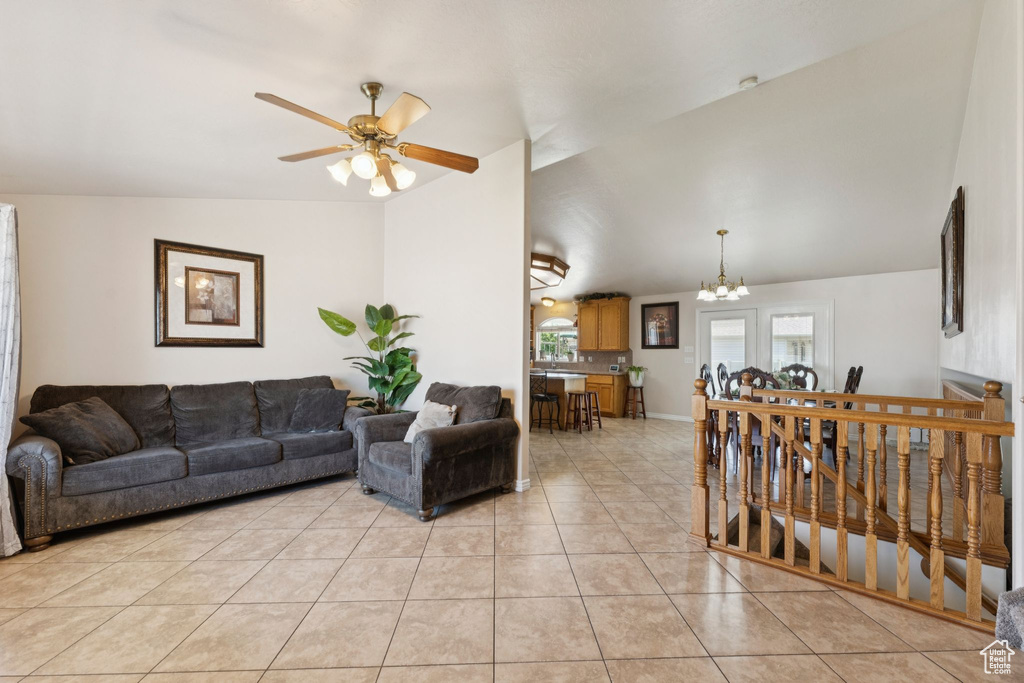 Living area with vaulted ceiling, a chandelier, a ceiling fan, and light tile patterned floors