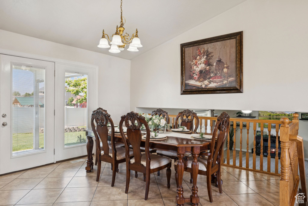 Dining area with vaulted ceiling, a chandelier, and light tile patterned flooring