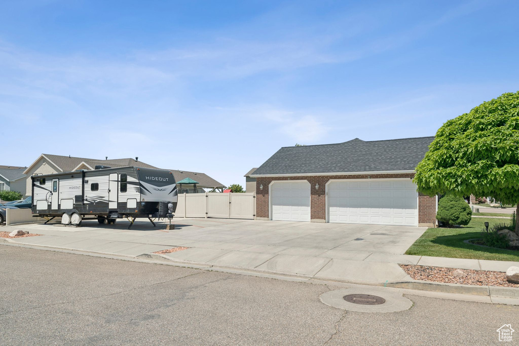 View of front of home with brick siding, concrete driveway, an attached garage, and a gate
