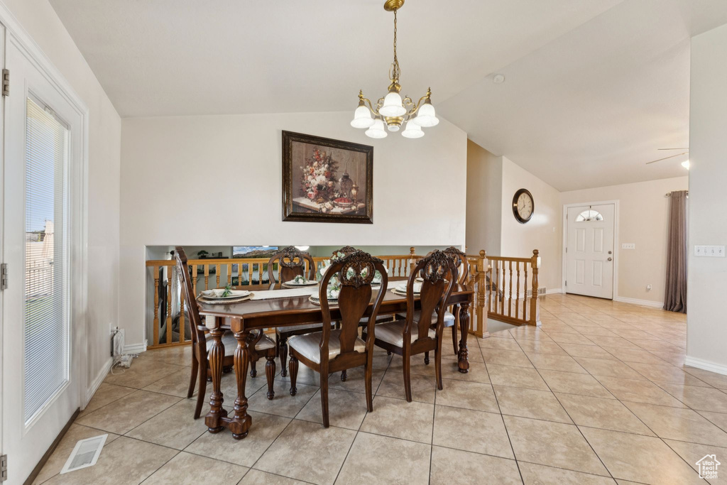 Dining room with light tile patterned floors, a chandelier, lofted ceiling, and baseboards