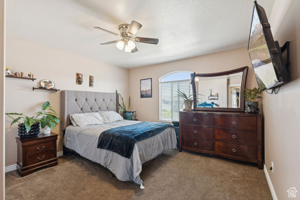 Carpeted bedroom featuring a ceiling fan and baseboards