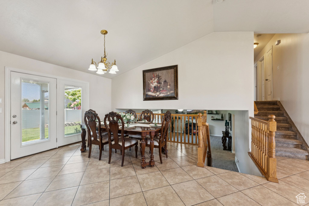 Dining space featuring lofted ceiling, light tile patterned floors, and a chandelier