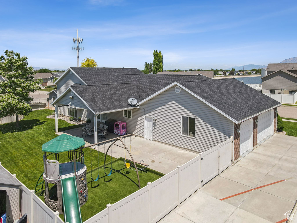 View of front of home featuring roof with shingles, a patio, driveway, and a gate