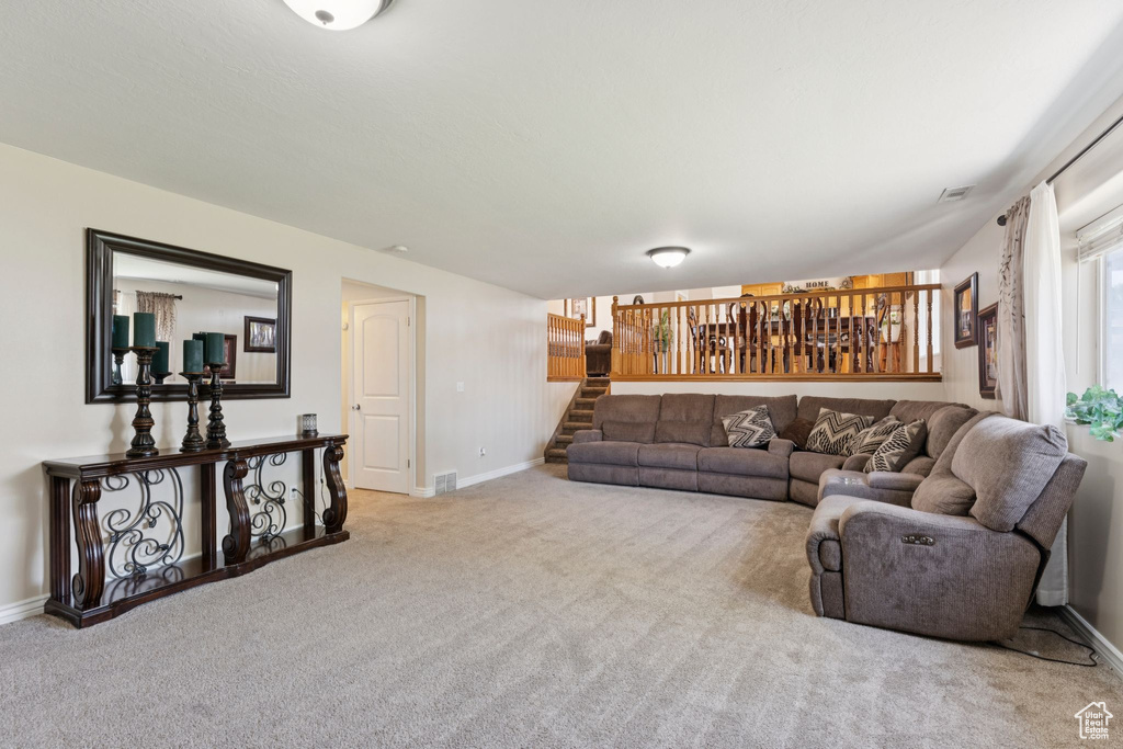 Living area featuring carpet floors, baseboards, and stairway