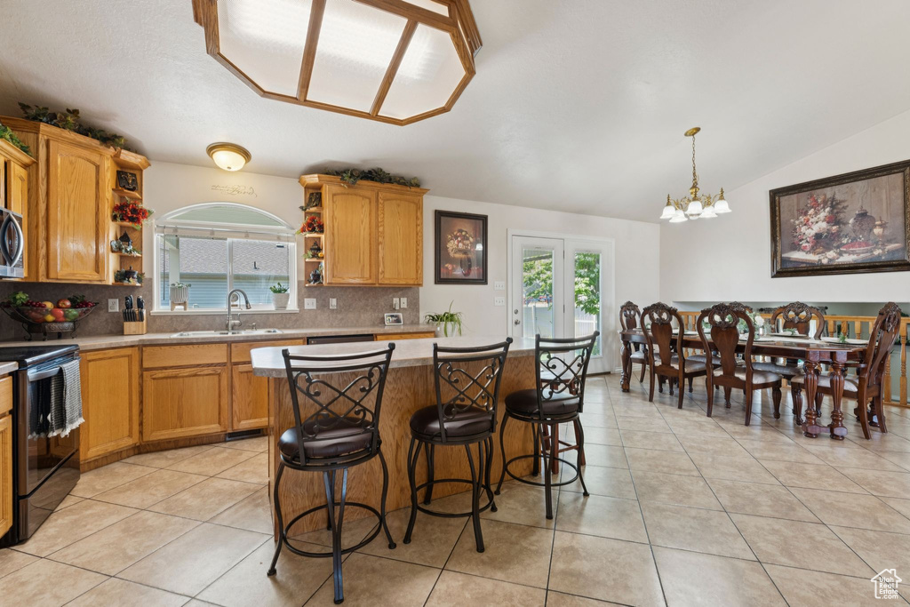 Kitchen featuring a sink, open shelves, appliances with stainless steel finishes, tasteful backsplash, and a chandelier