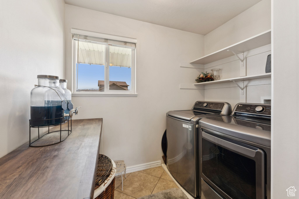 Laundry area featuring washing machine and clothes dryer, baseboards, and tile patterned flooring