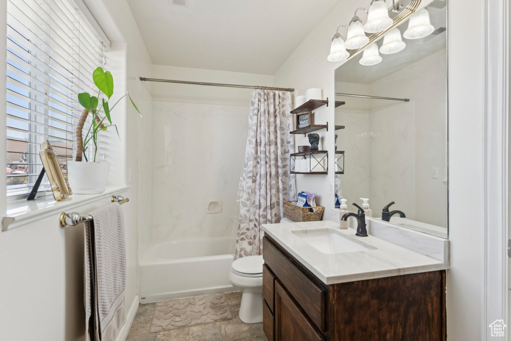 Bathroom featuring vanity, shower / bath combo, toilet, and a chandelier