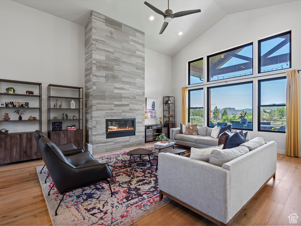Living area with high vaulted ceiling, a tile fireplace, ceiling fan, wood finished floors, and recessed lighting