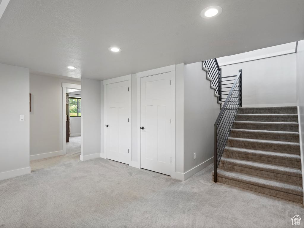 Below grade area with baseboards, stairs, recessed lighting, and carpet flooring