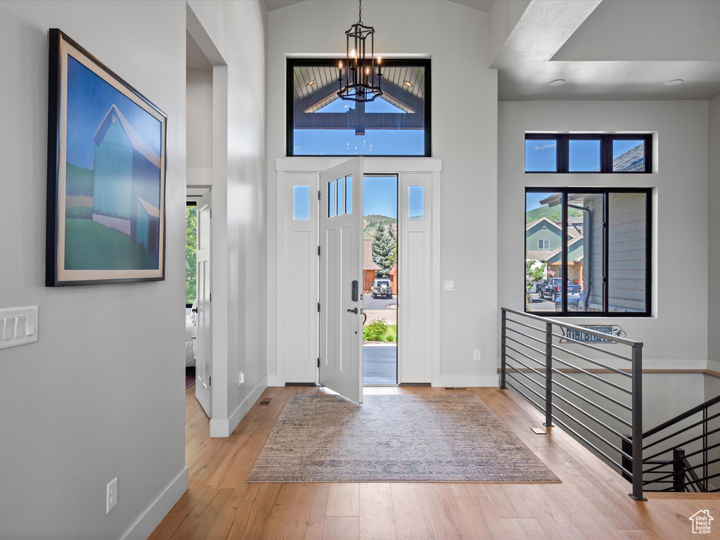 Entrance foyer featuring a chandelier, baseboards, wood finished floors, and a towering ceiling