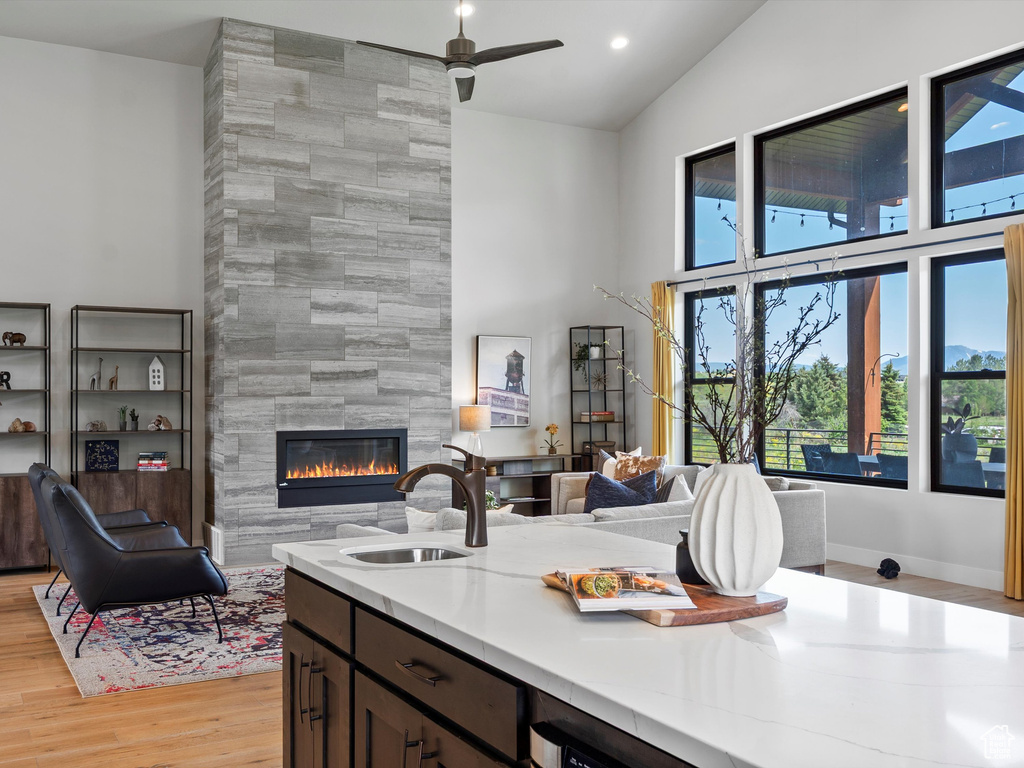 Kitchen featuring a sink, high vaulted ceiling, open floor plan, a fireplace, and light wood-style floors