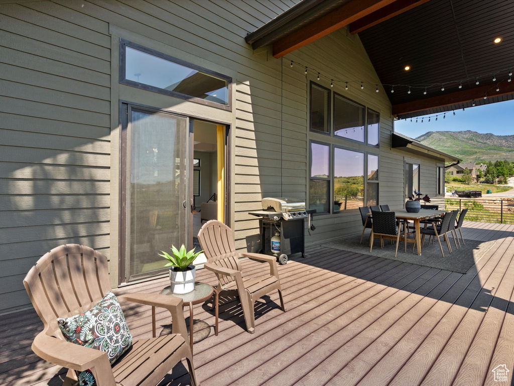 Wooden terrace featuring area for grilling, outdoor dining area, and a mountain view