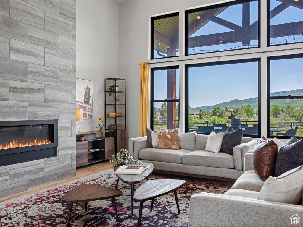 Living area featuring a fireplace, a high ceiling, a mountain view, and wood finished floors