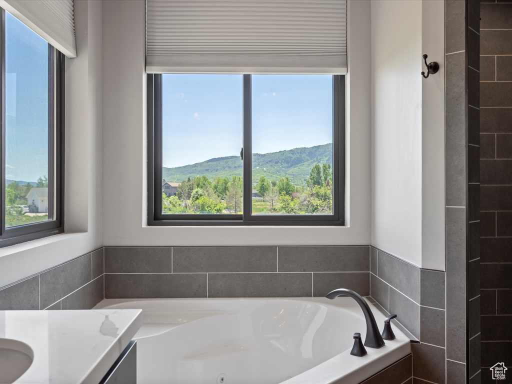 Full bath featuring plenty of natural light, a tub with jets, and vanity