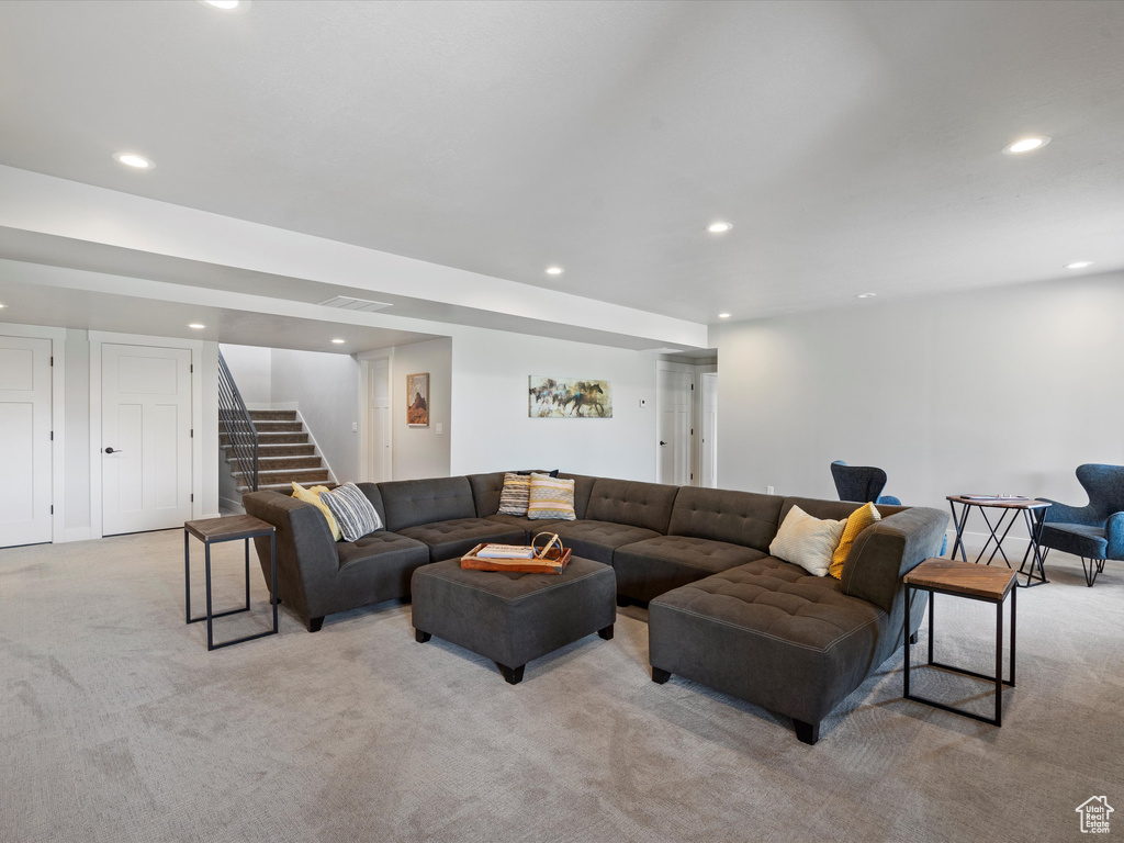 Living area with light carpet, recessed lighting, and stairs