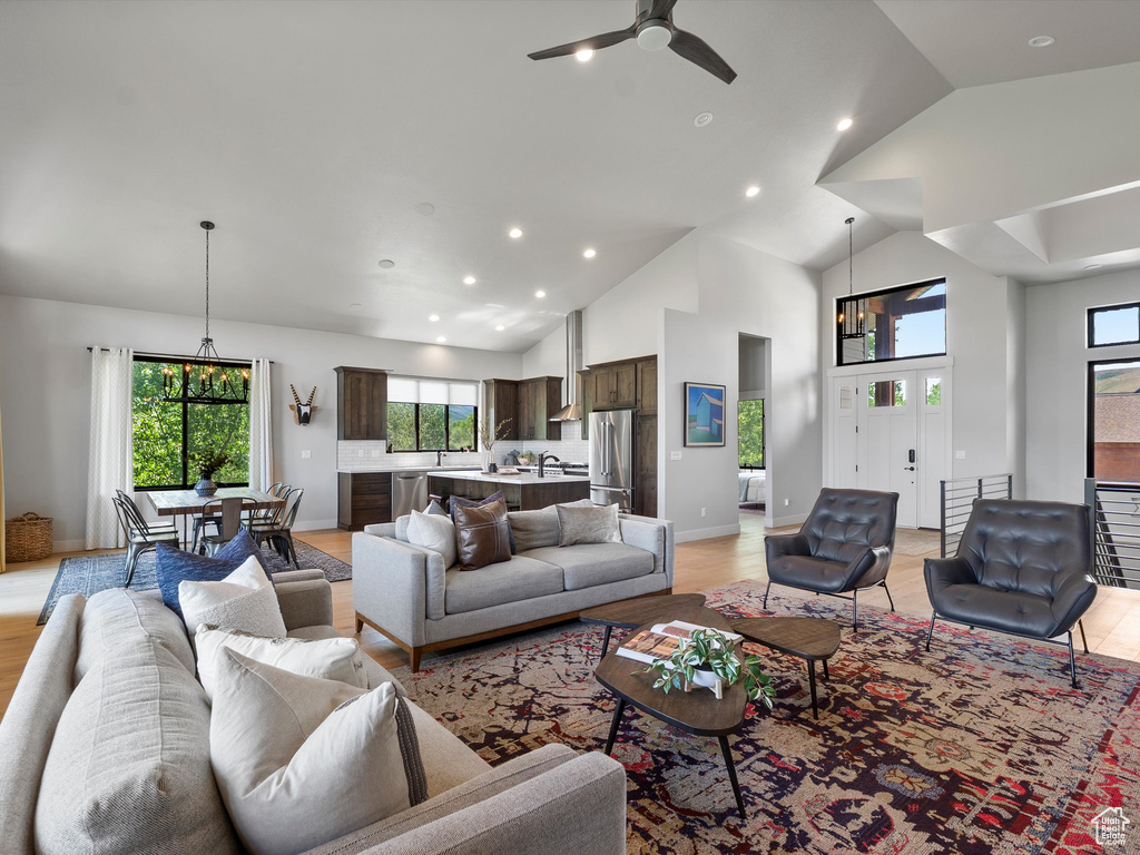 Living area with recessed lighting, plenty of natural light, a ceiling fan, high vaulted ceiling, and light wood-style floors