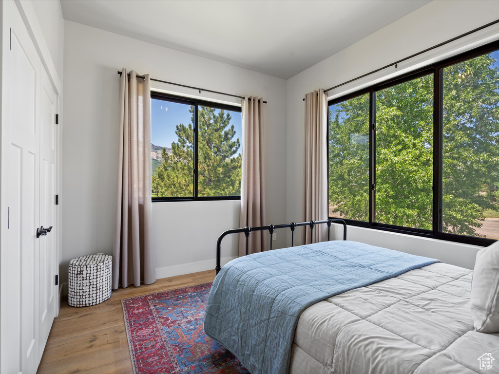 Bedroom with multiple windows, wood finished floors, and baseboards