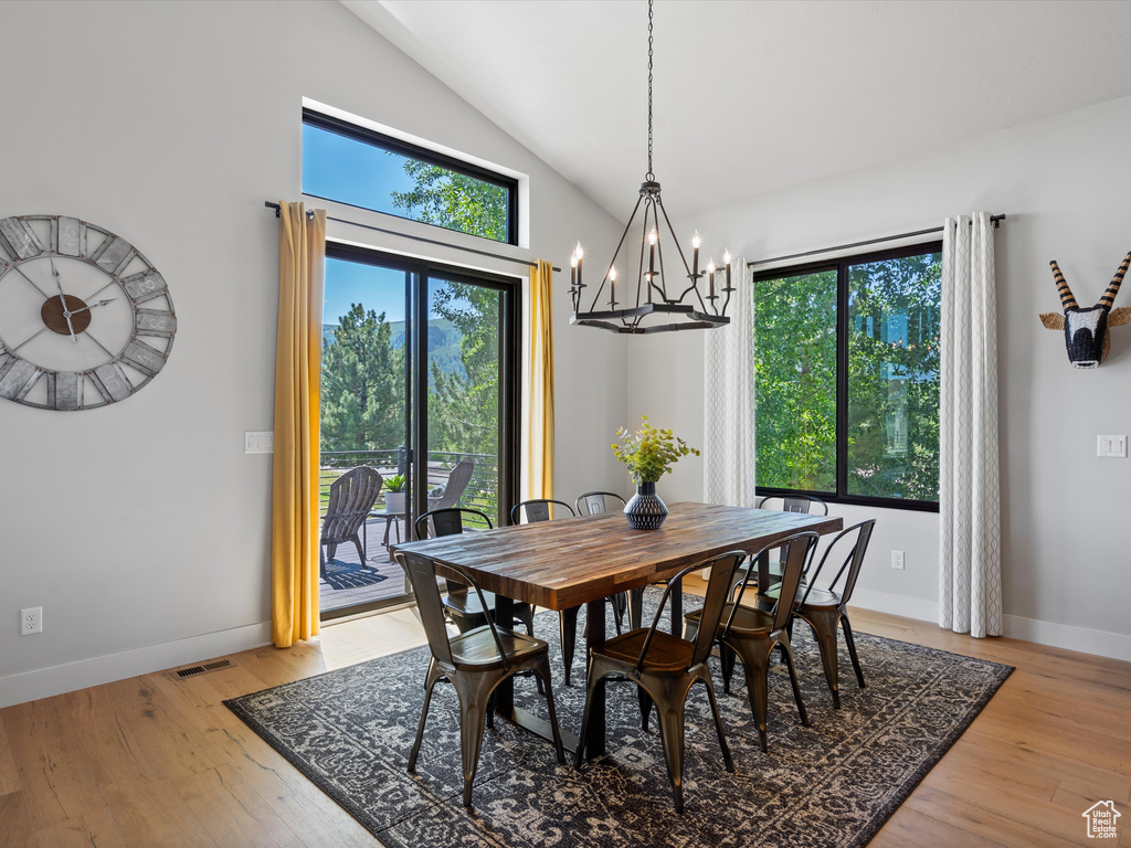 Dining room with a chandelier, plenty of natural light, baseboards, and high vaulted ceiling