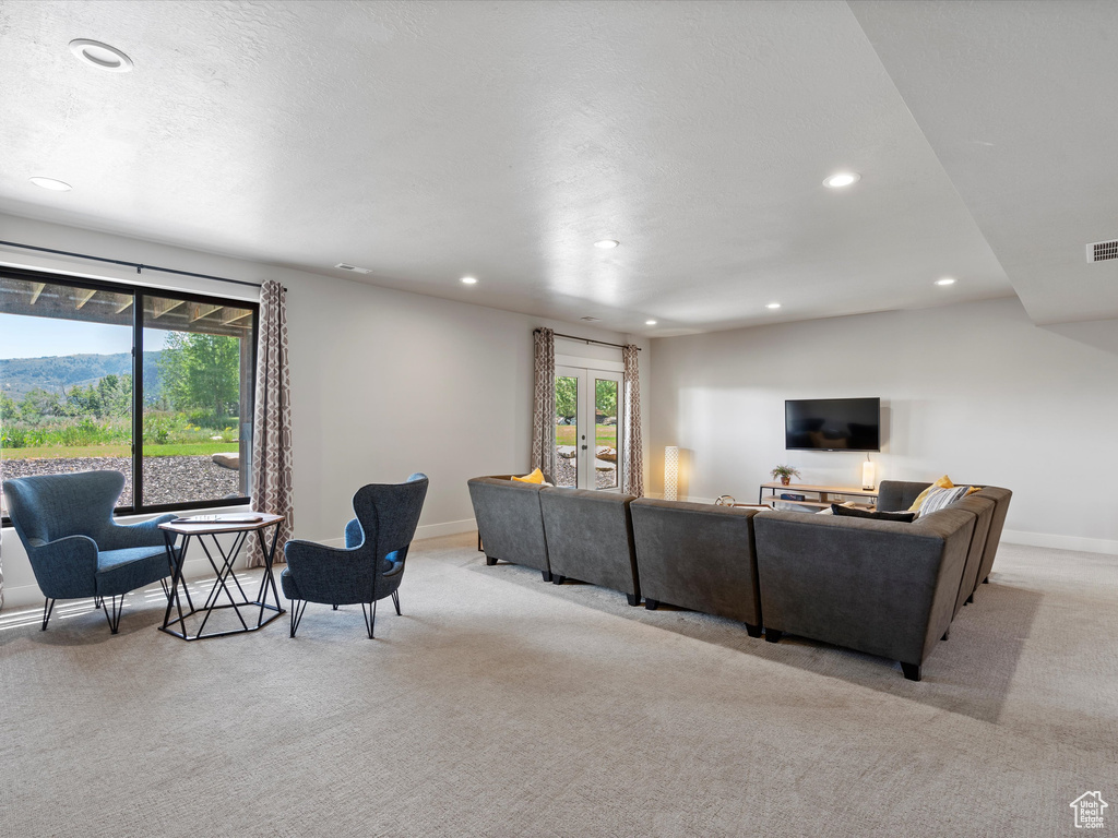 Living area with light carpet, recessed lighting, healthy amount of natural light, and baseboards