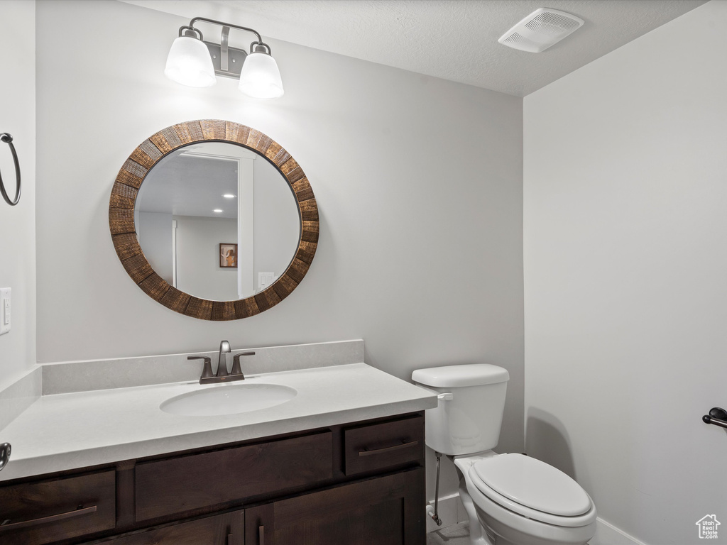 Bathroom featuring vanity, toilet, and baseboards