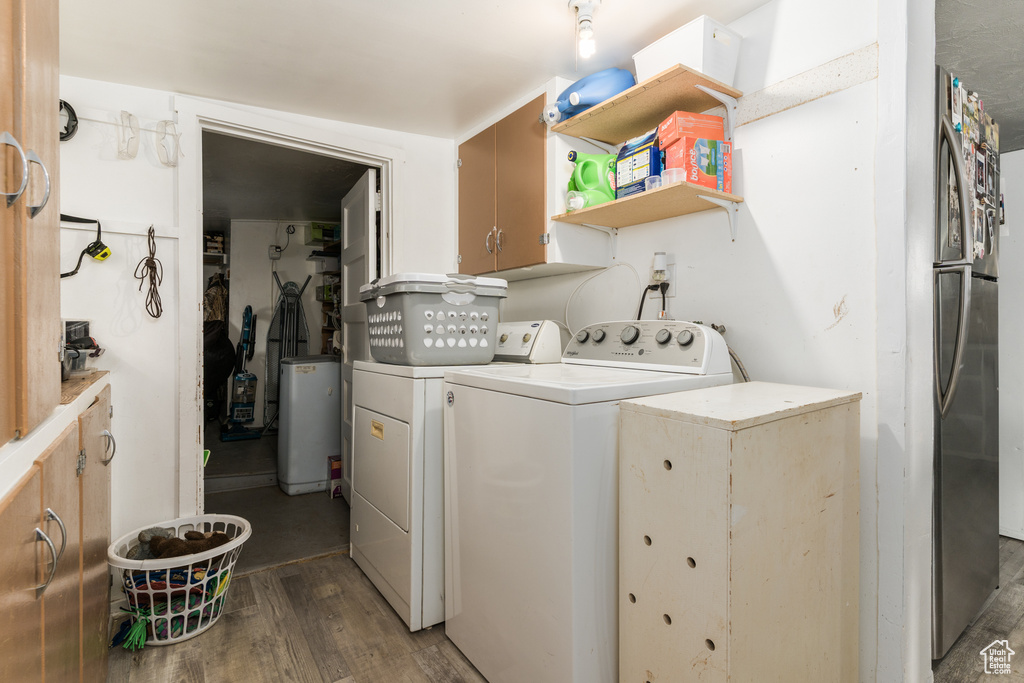 Laundry room with washing machine and dryer, wood finished floors, and cabinet space