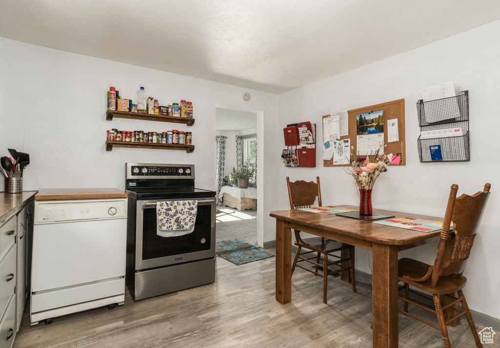 Kitchen with stainless steel range with electric cooktop, white dishwasher, and light wood-type flooring