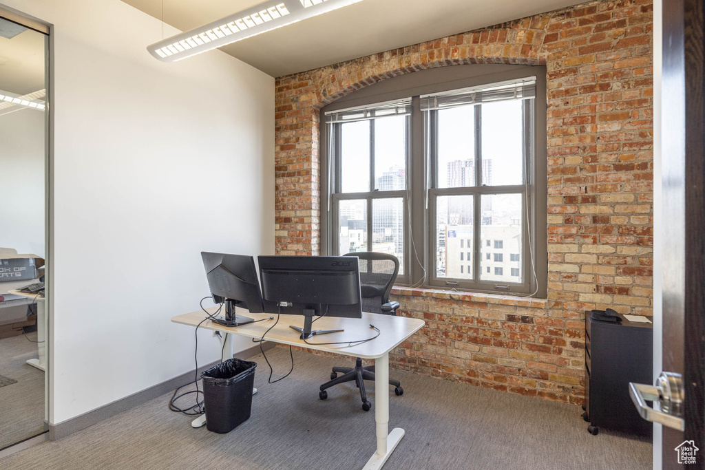 Office area featuring carpet and brick wall