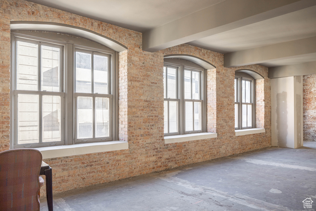 Spare room featuring brick wall and beamed ceiling