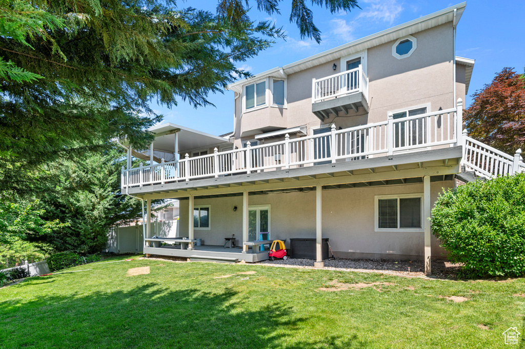 Back of house featuring stucco siding, a deck, and a yard