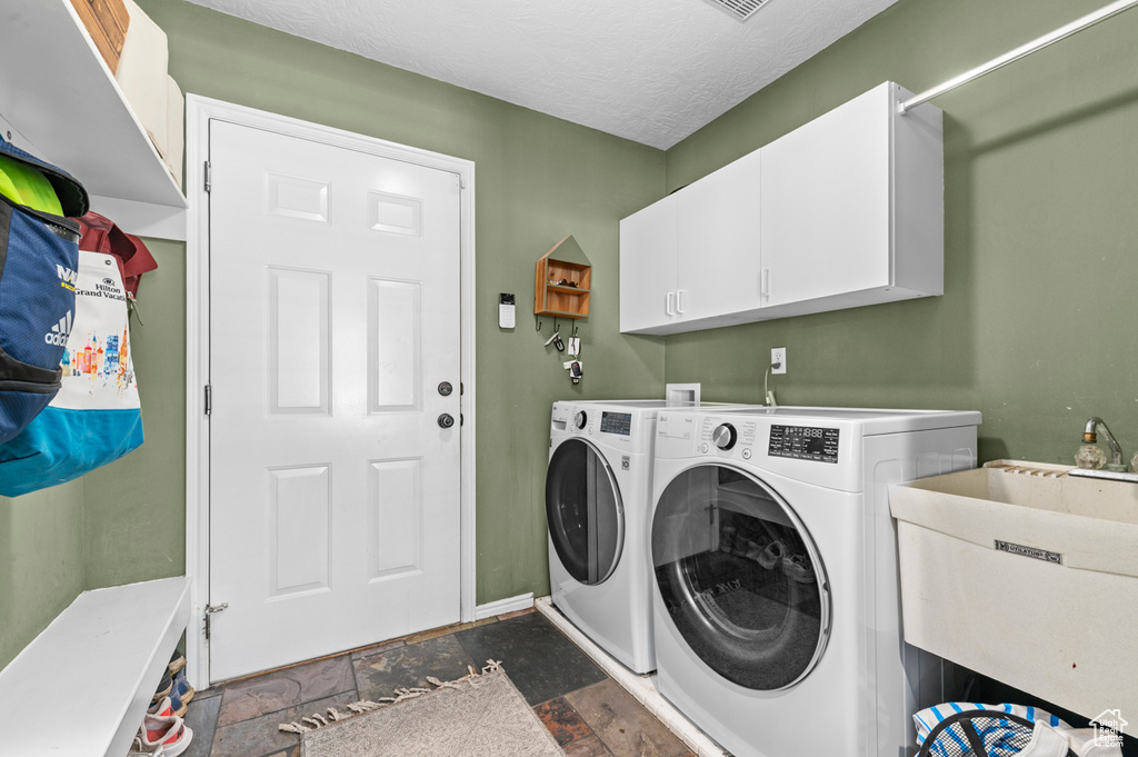 Washroom with separate washer and dryer, cabinet space, dark stone finish floors, and baseboards