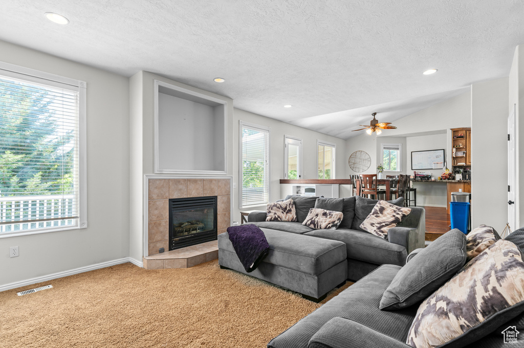 Carpeted living area with a textured ceiling, a tile fireplace, ceiling fan, baseboards, and recessed lighting