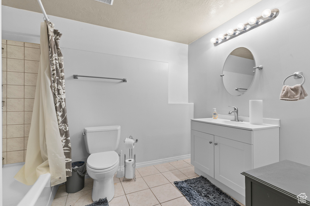 Full bath with vanity, shower / bath combo, toilet, and tile patterned floors