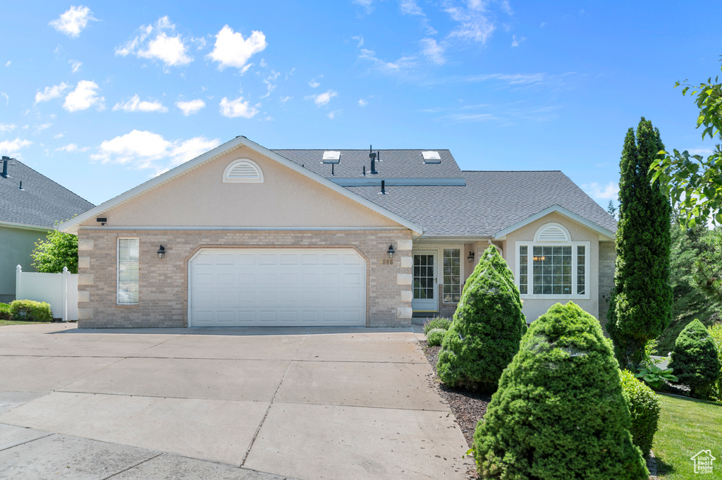 View of front of home featuring driveway, a garage, brick siding, and roof with shingles