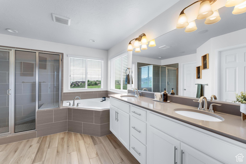 Bathroom with double vanity, a shower stall, and a garden tub