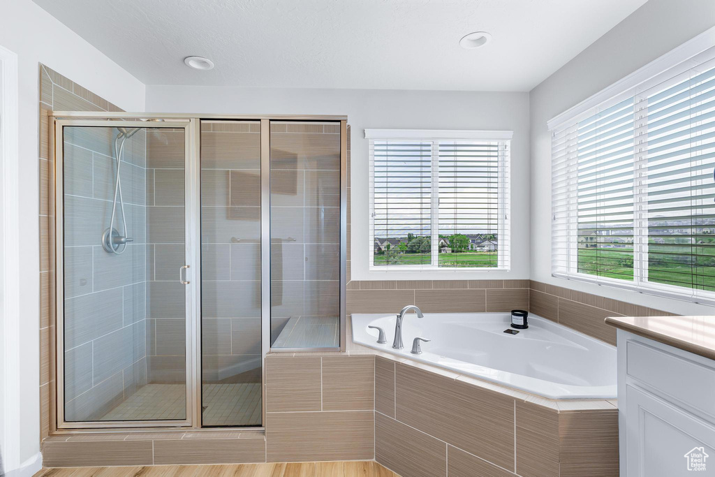 Bathroom with a garden tub, a stall shower, and vanity