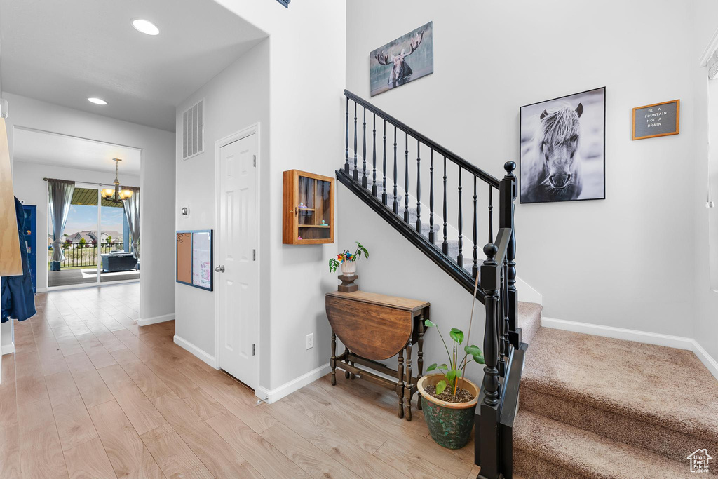 Stairway with a chandelier, baseboards, recessed lighting, and wood finished floors
