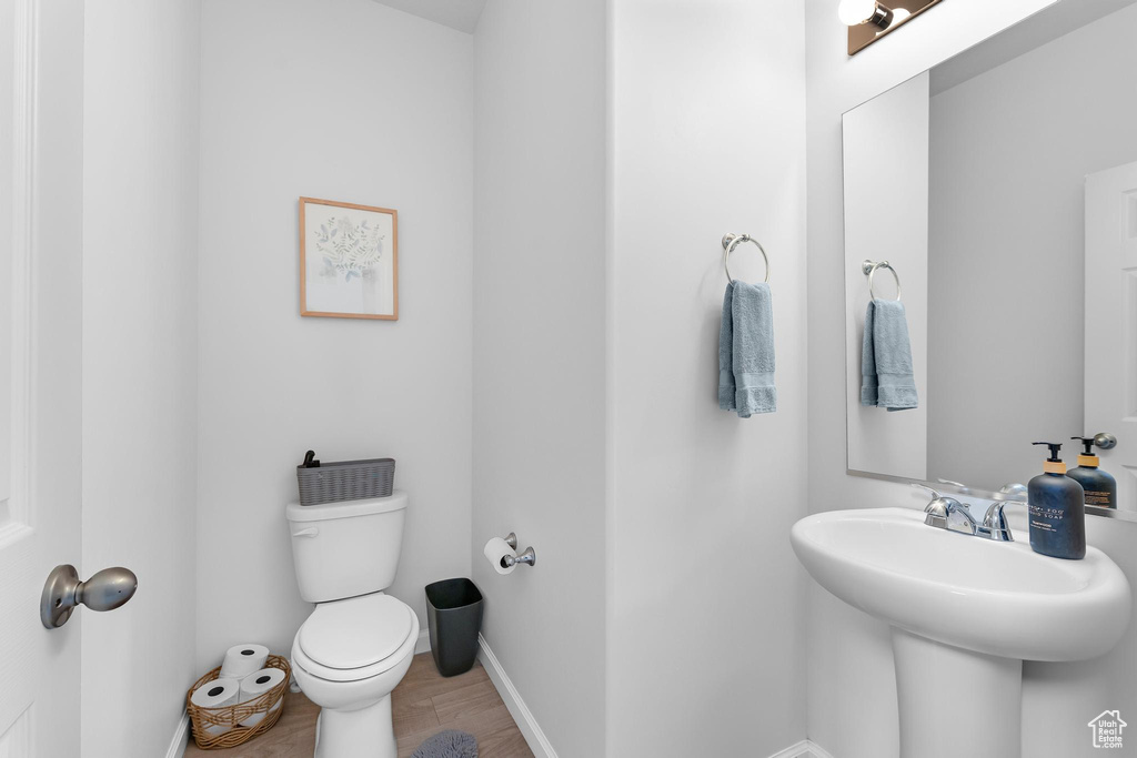 Half bath with toilet, baseboards, and wood finished floors