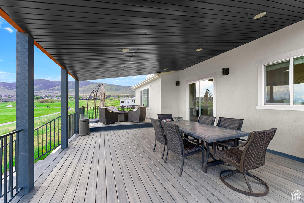 Wooden terrace featuring a mountain view, outdoor dining area, outdoor lounge area, and view of golf course