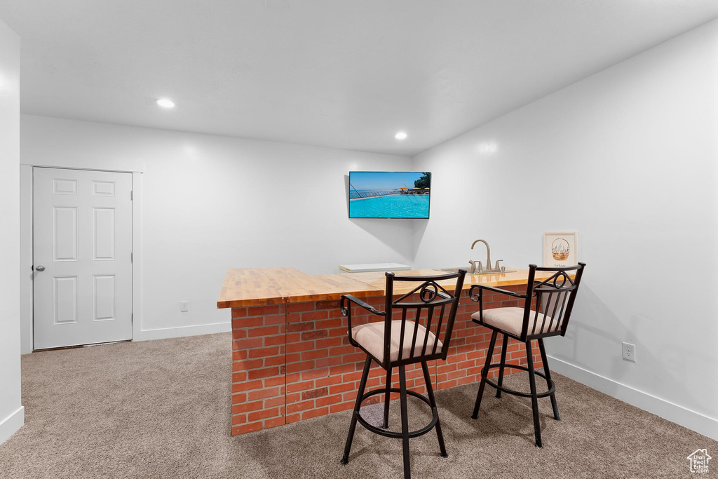 Carpeted dining room featuring bar with sink, baseboards, and recessed lighting