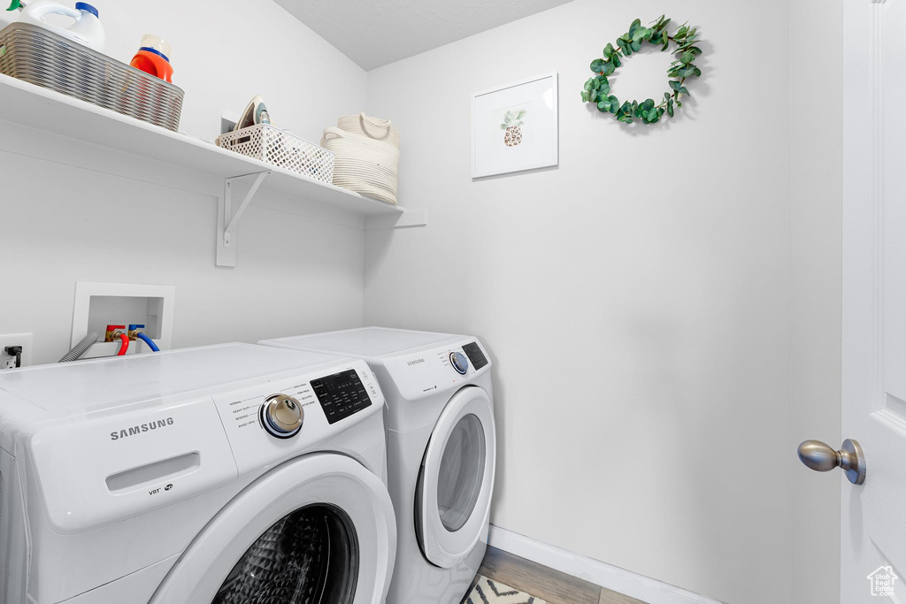 Laundry area featuring washer and dryer, light wood-style floors, and baseboards