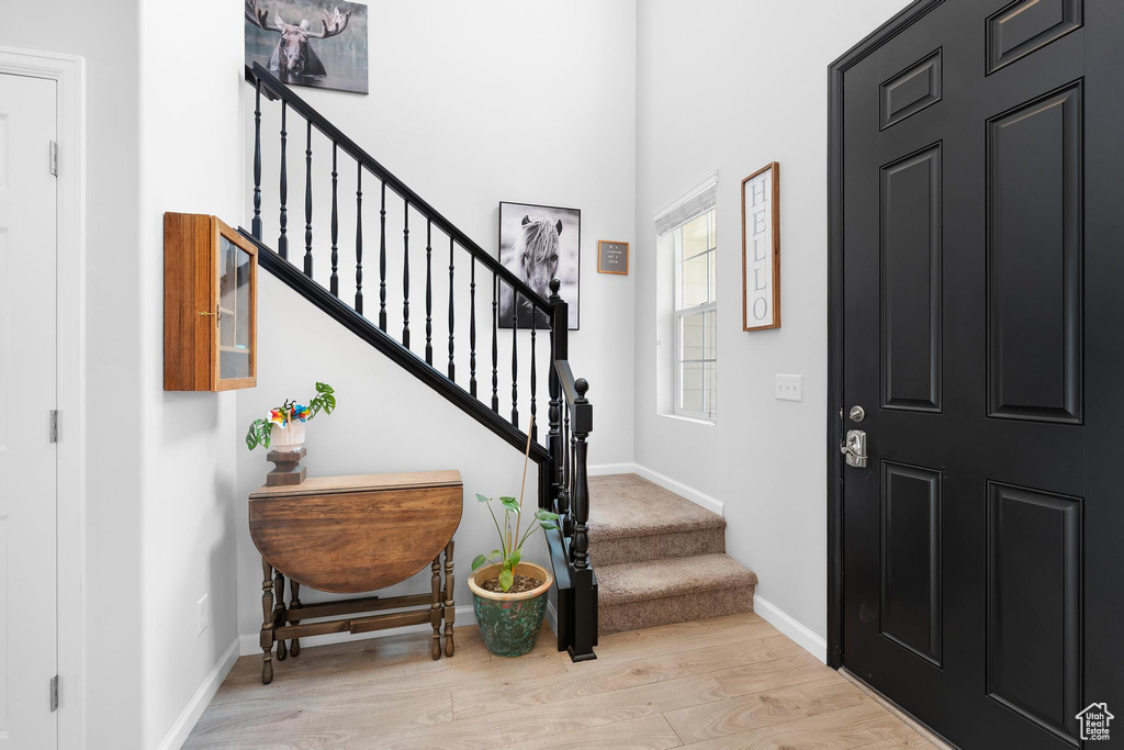 Entrance foyer with wood finished floors, stairway, and baseboards