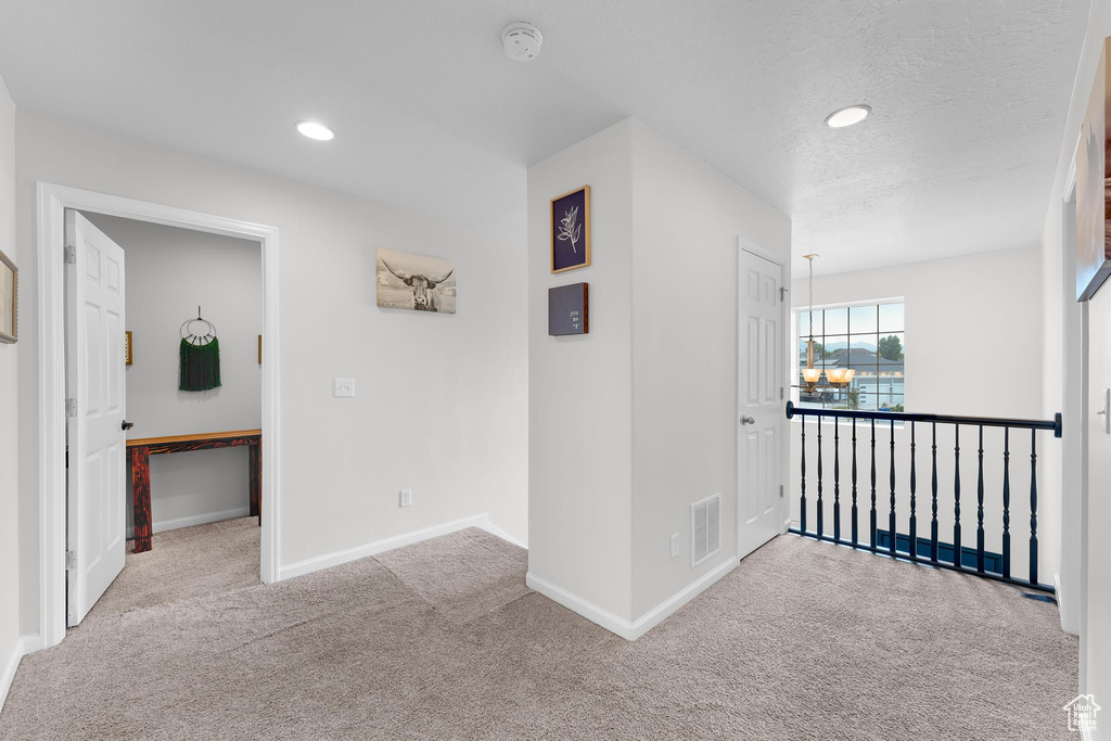 Hall featuring carpet, baseboards, recessed lighting, a chandelier, and a textured ceiling