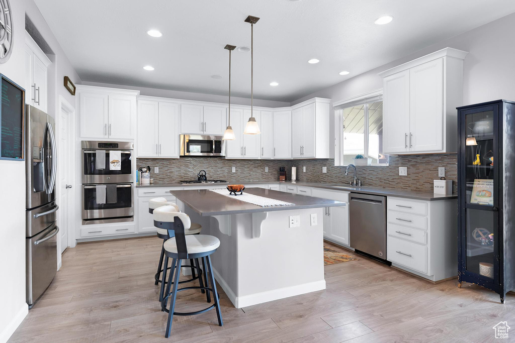Kitchen with appliances with stainless steel finishes, a sink, backsplash, a center island, and recessed lighting