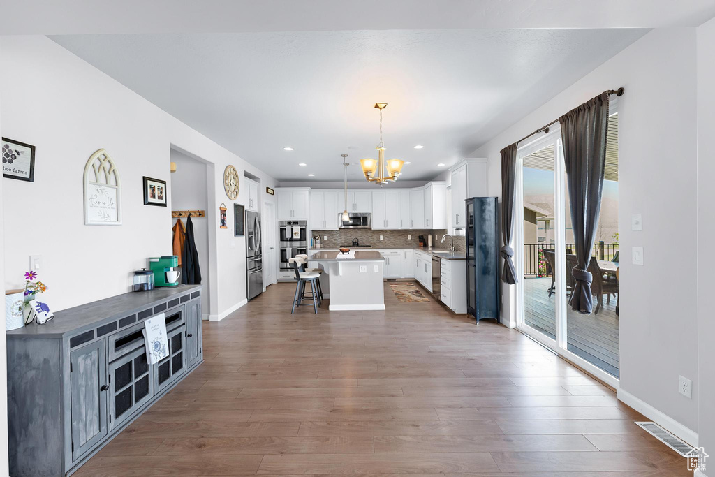 Kitchen featuring stainless steel appliances, a chandelier, a kitchen breakfast bar, a sink, and a kitchen island