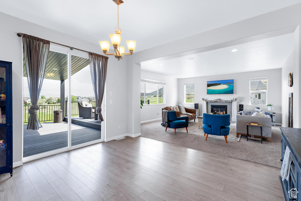 Living area with a glass covered fireplace, a chandelier, baseboards, and wood finished floors