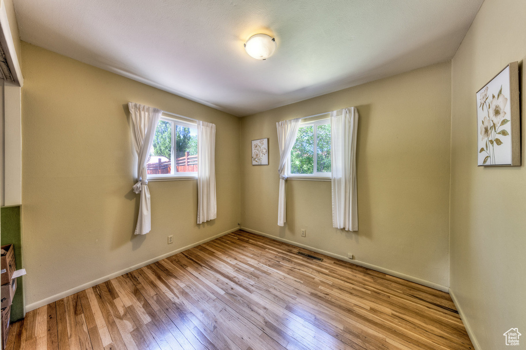 Spare room featuring healthy amount of natural light, wood-type flooring, and baseboards