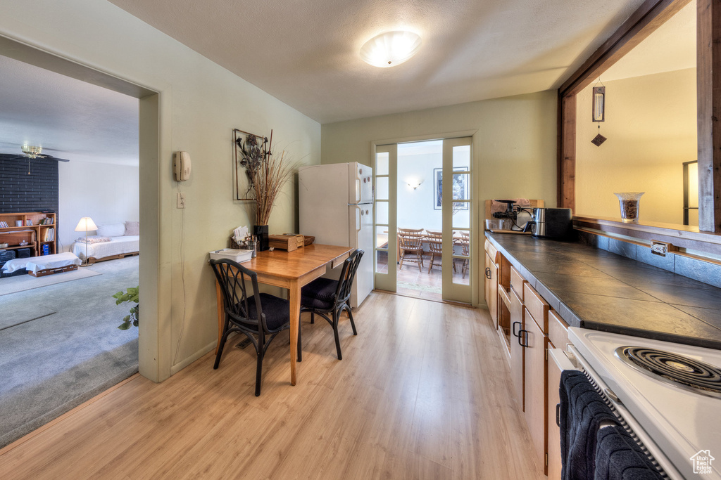Kitchen with white appliances, light wood-type flooring, and dark countertops